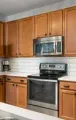 A kitchen with light wood cabinets, stainless steel appliances, white subway tile backsplash, and a white countertop.