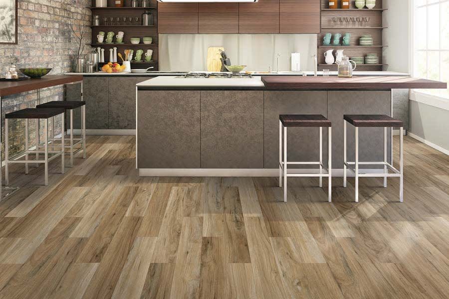 Modern kitchen with wood-look flooring, a central island with bar stools, brick wall, and open shelving.