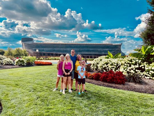 A family is posing for a picture in front of The Ark Encounter.