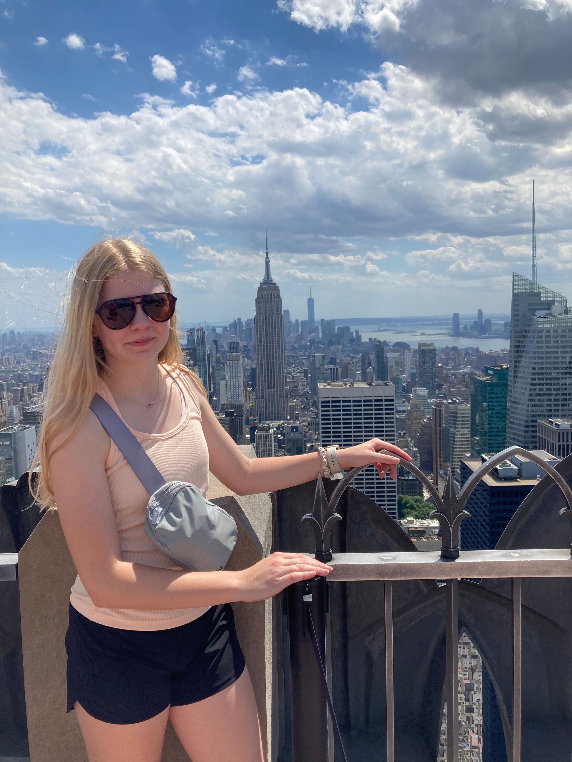 A woman is standing on top of a building with New York city in the background.
