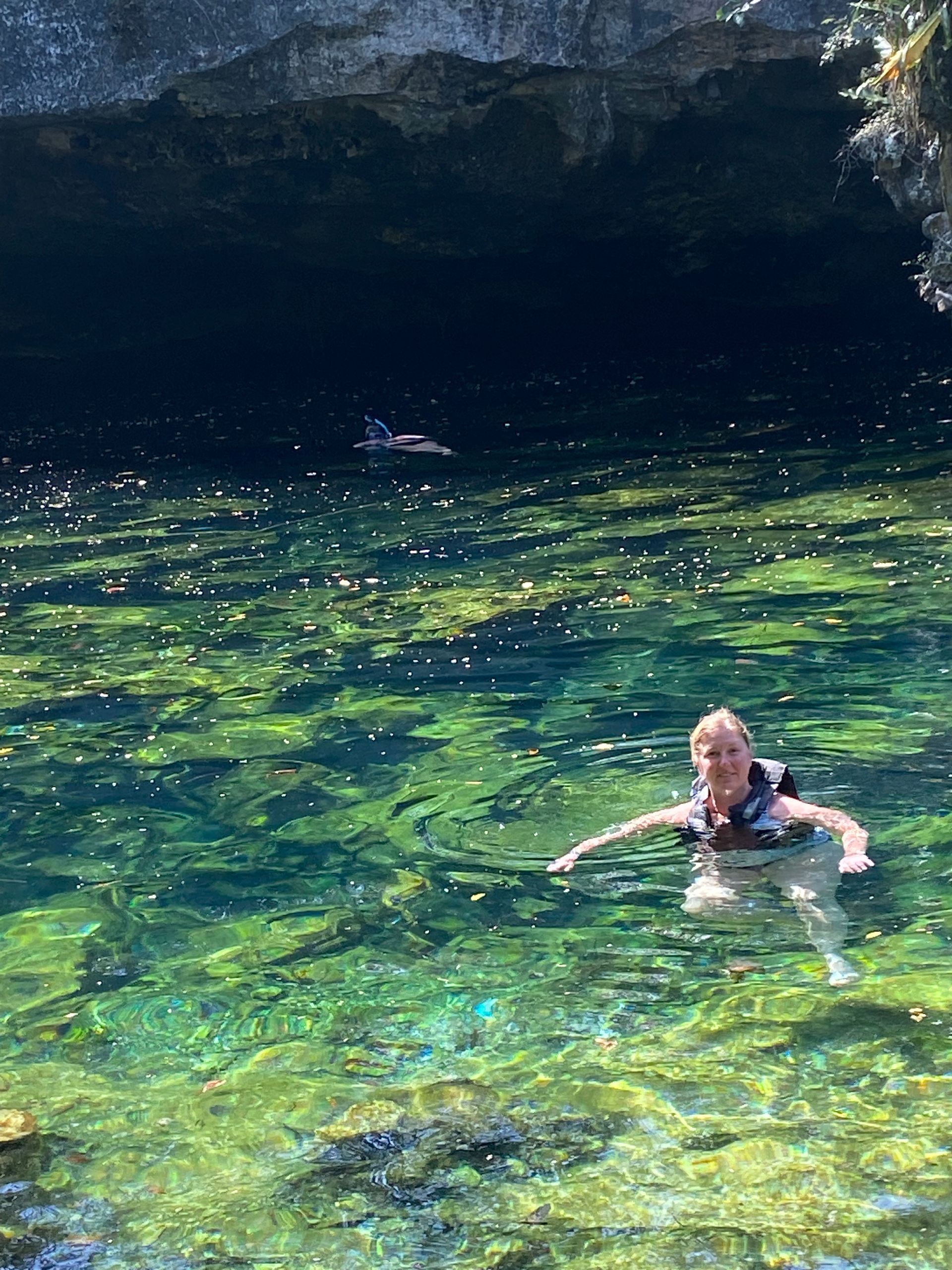 A woman is swimming in a Cenote.