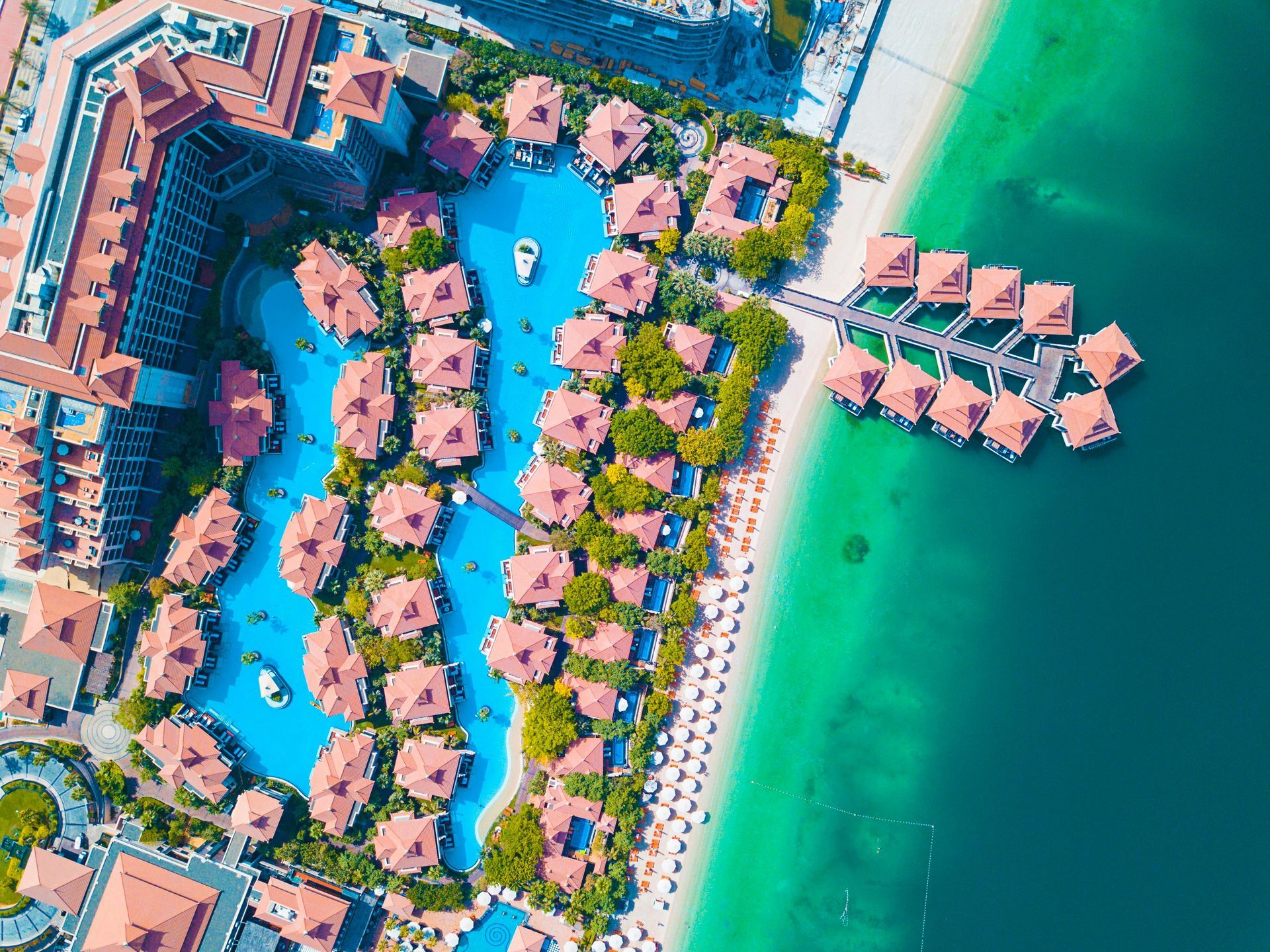 An aerial view of a tropical resort with a large pool and a beach.
