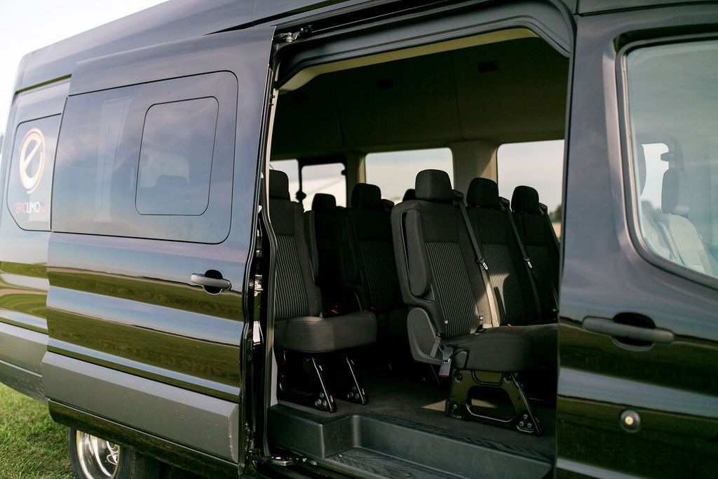 Black passenger van with open side door, revealing rows of seats.