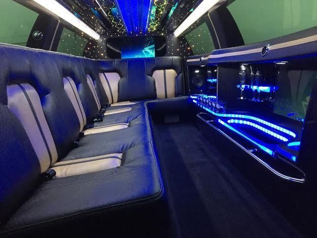 Interior of a luxury limousine with blue and white leather seating, lit with blue LED lights.