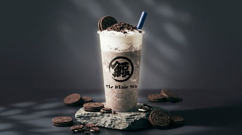 Chocolate milkshake with whipped cream and cookie garnish on a dark surface, surrounded by scattered cookies.