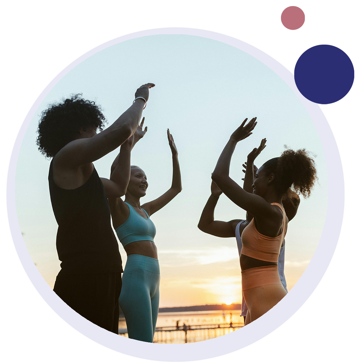 A group of women in exercise clothes are raising their arms in the air.