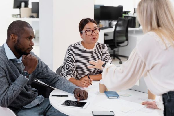 A group of people are sitting around a table having a meeting.