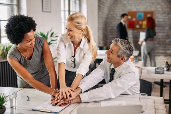 A group of people are putting their hands together in an office.
