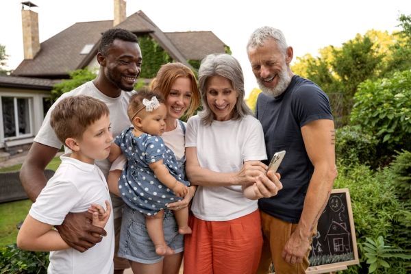 A multiracial family group is posing for a picture in front of a house.