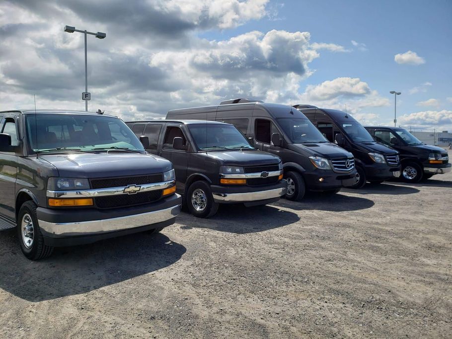 A row of vans are parked in a parking lot.
