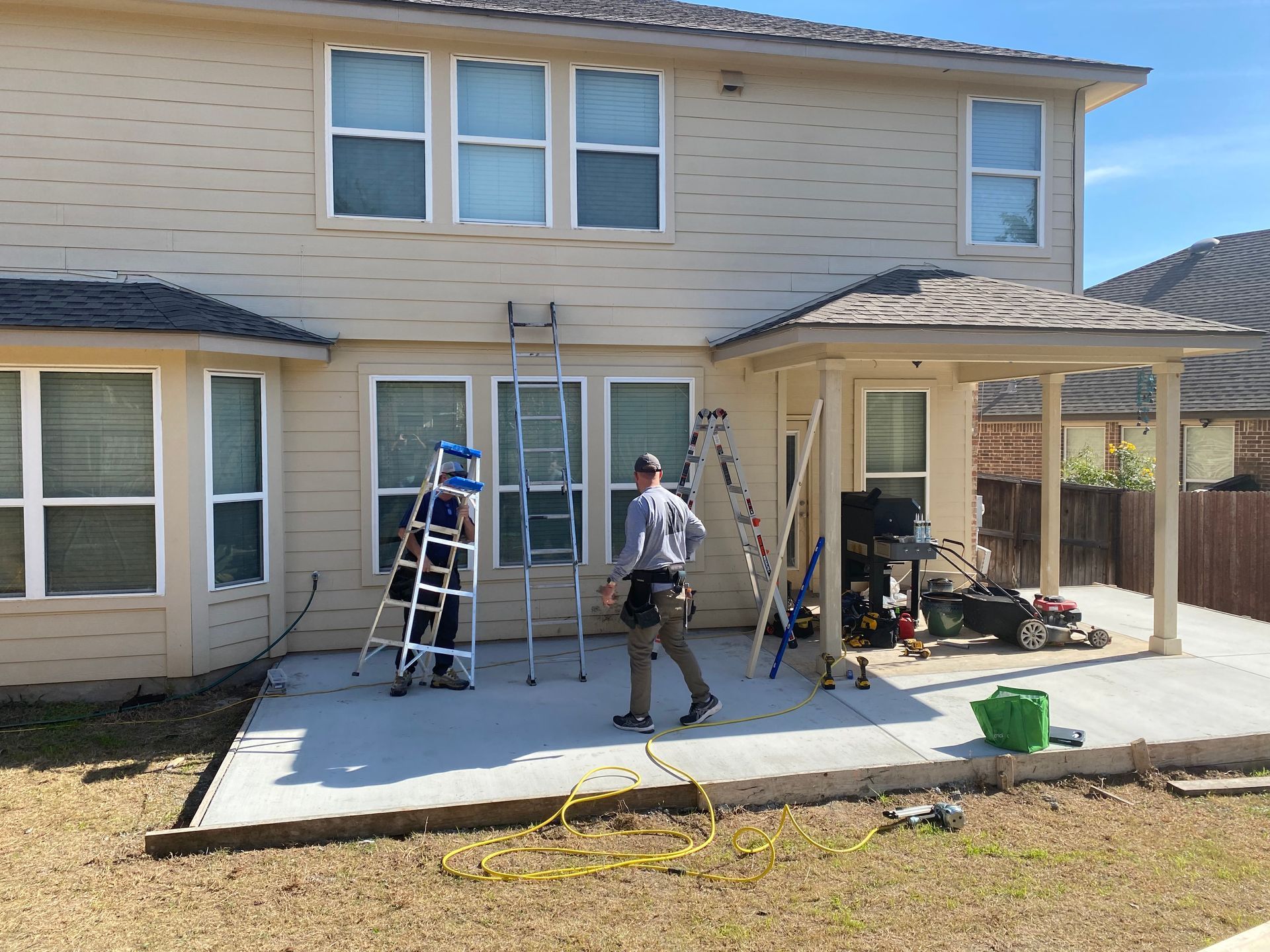 A man is standing in front of a house with a ladder.