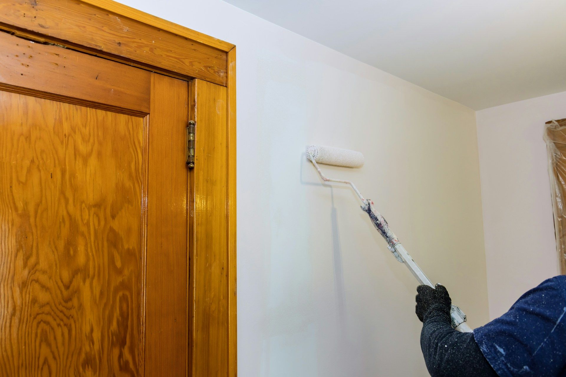 A person in black gloves reaches into an open toilet tank to adjust the green flush valve and chain.