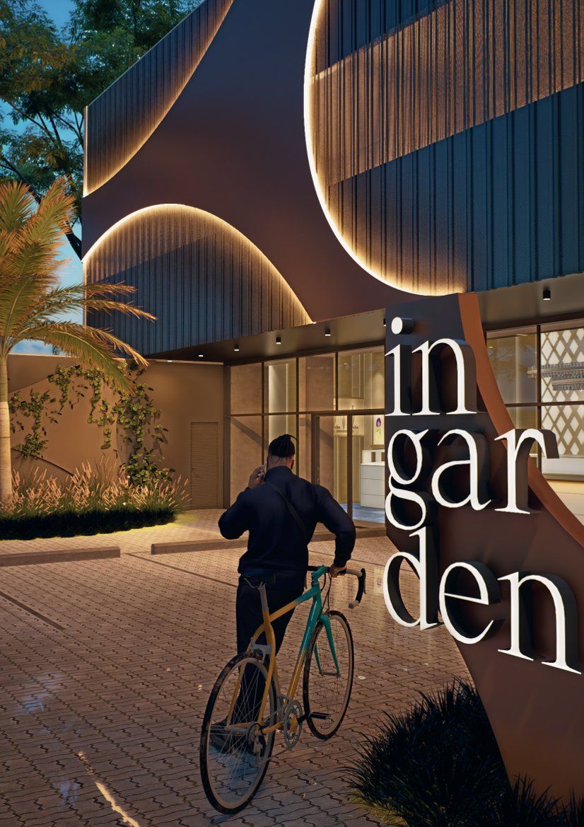 Ciclista entrando em um prédio moderno e aconchegante ao entardecer, com sinalização iluminada indicando 