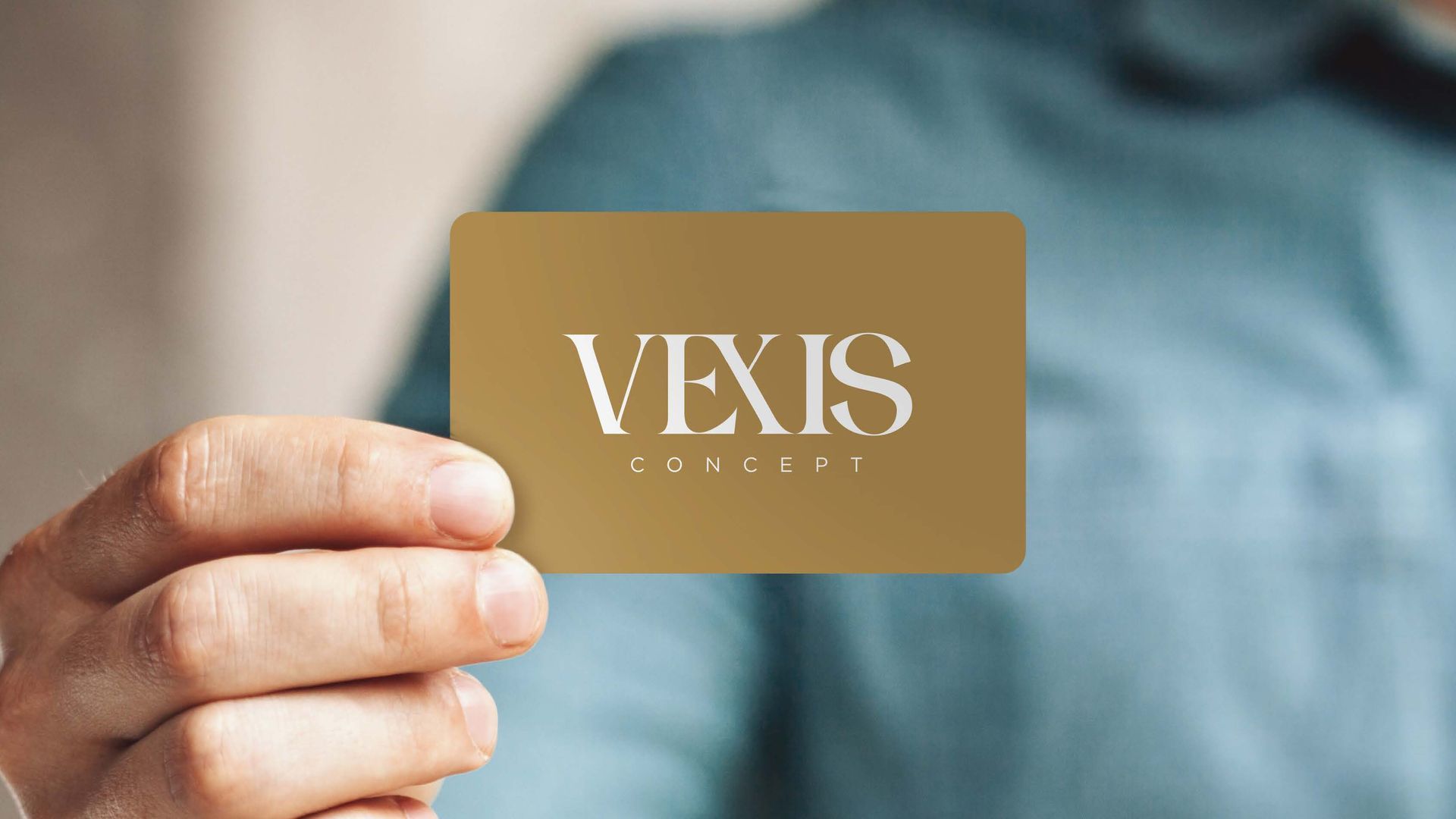 Pessoa segurando um cartão de visita dourado com o logotipo 