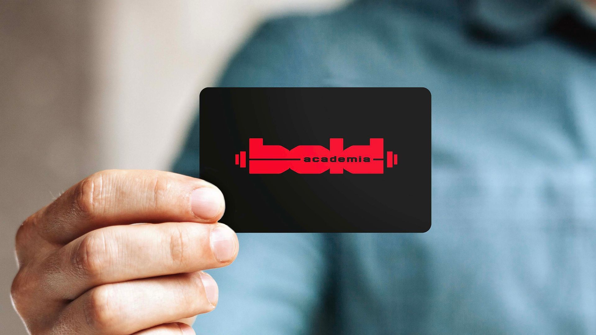 Mão segurando um cartão preto com um logotipo vermelho em formato de equalizador sobre um fundo desfocado.