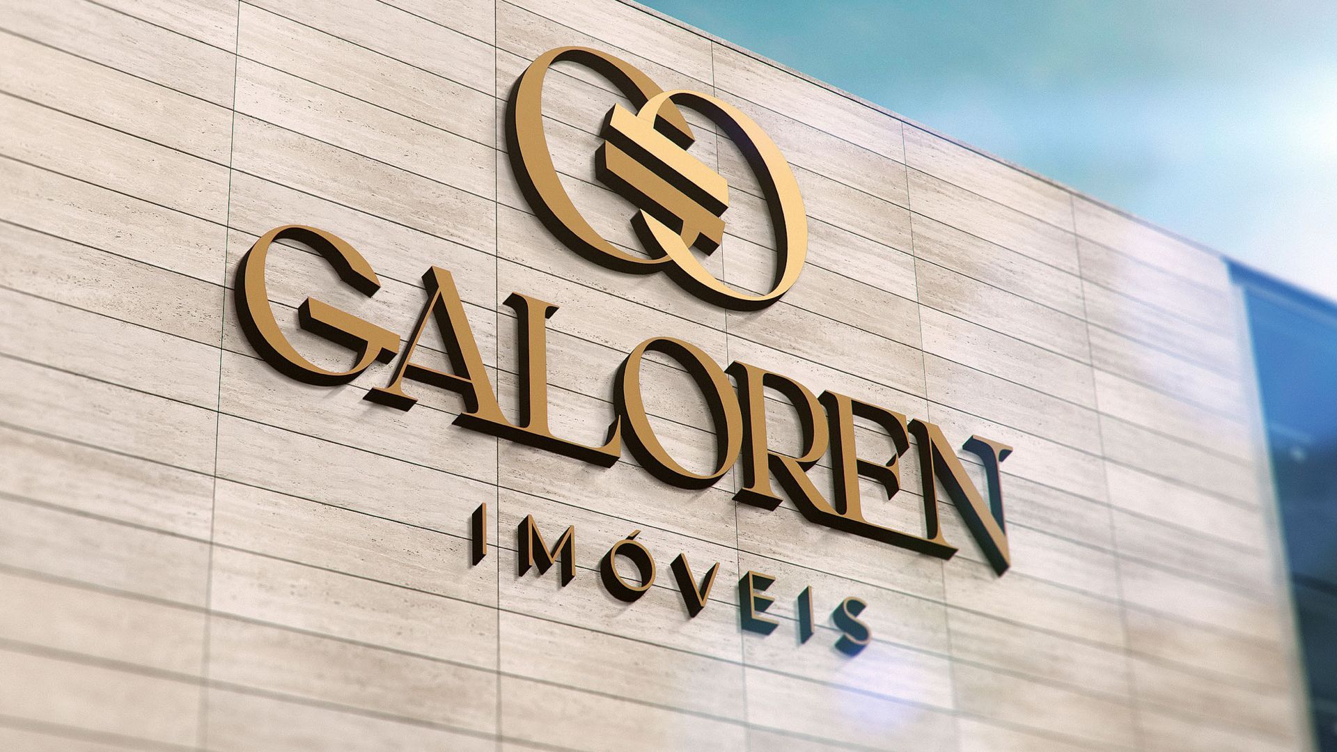 Placa dourada com a inscrição “GALORN IMOVEIS” em uma parede de pedra clara, com um logotipo circular acima.