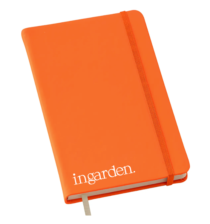Caderno laranja com elástico e marcador de fita sobre fundo branco