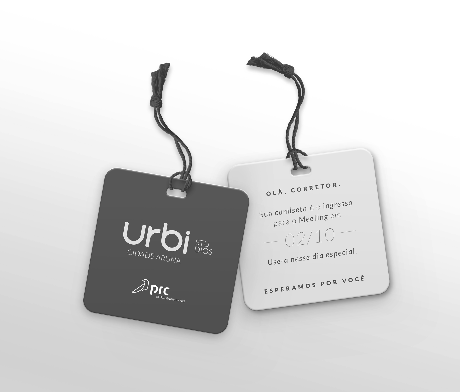 Duas etiquetas quadradas para roupas, uma preta e uma branca, com cordão preto preso sobre fundo branco.