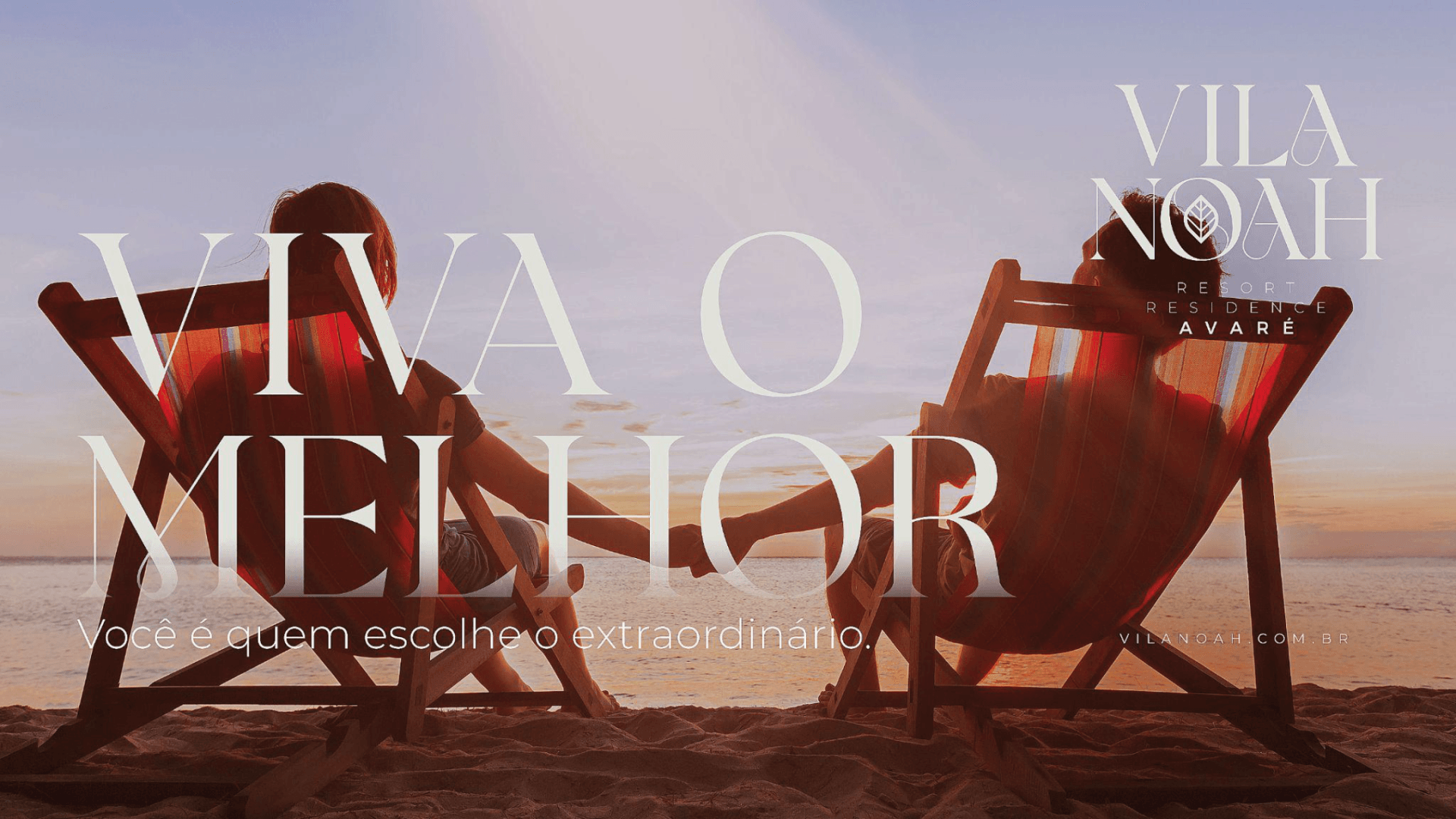 Duas pessoas relaxam em cadeiras de praia ao pôr do sol, de mãos dadas. Texto: 