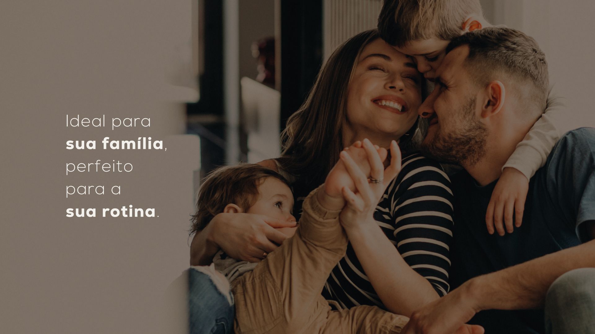 Família aconchegada em um sofá, com um bebê em uma sala de estar acolhedora e com iluminação suave.