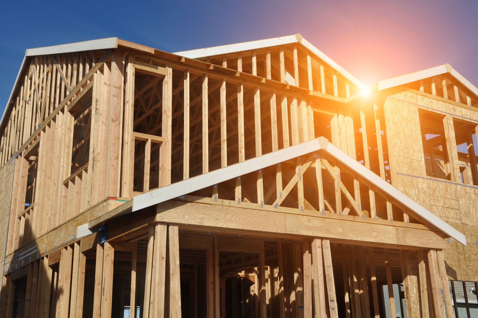 Wooden house under construction; frame structure against a bright sunny sky.