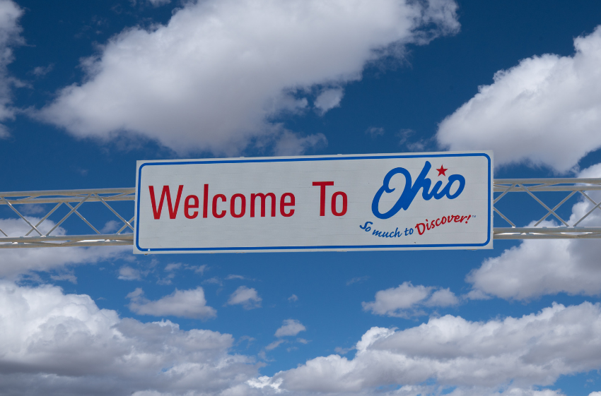Welcome to Ohio sign against a blue sky with clouds