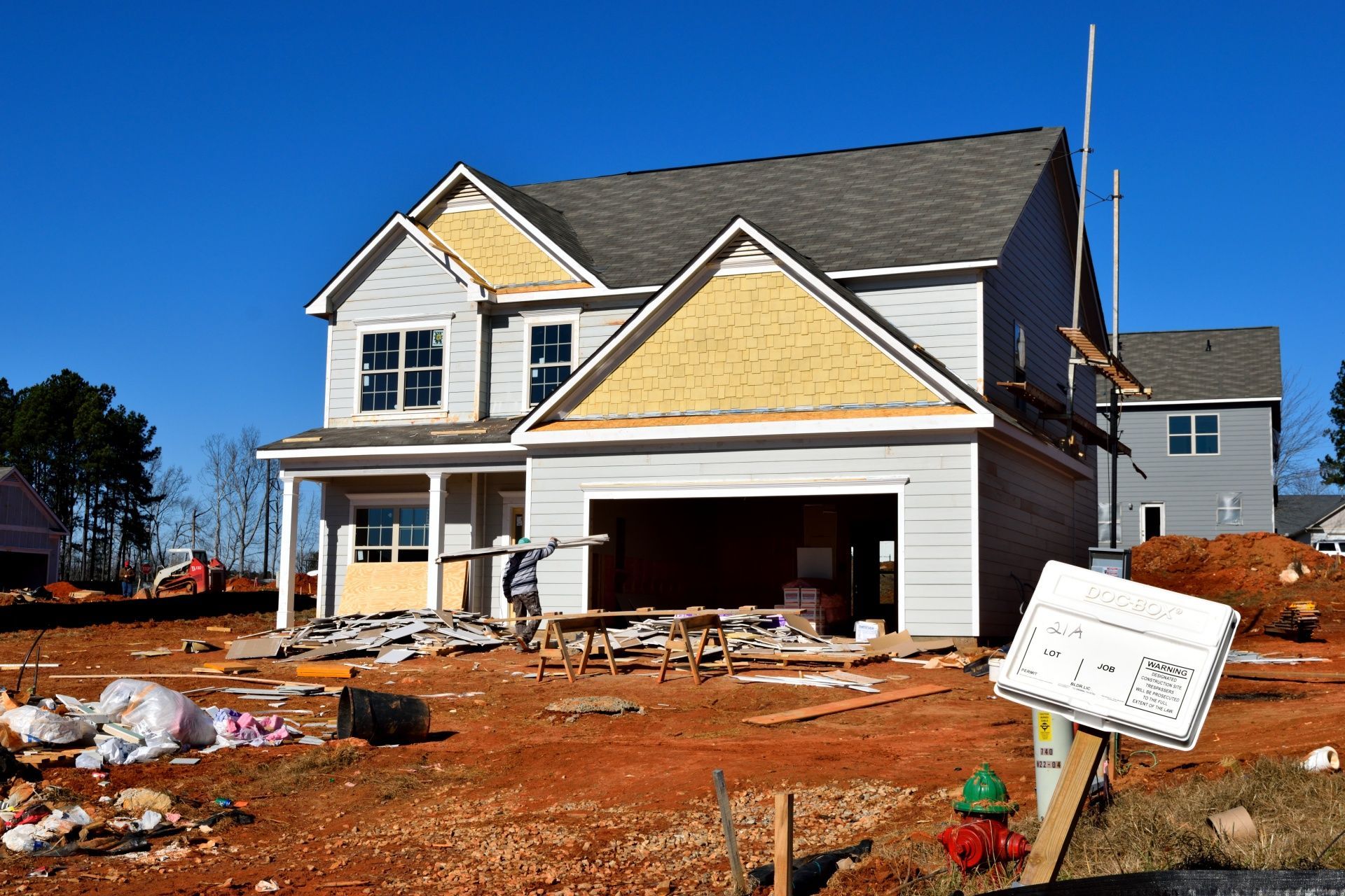 House under construction with exposed wood, blue siding, and a worker.