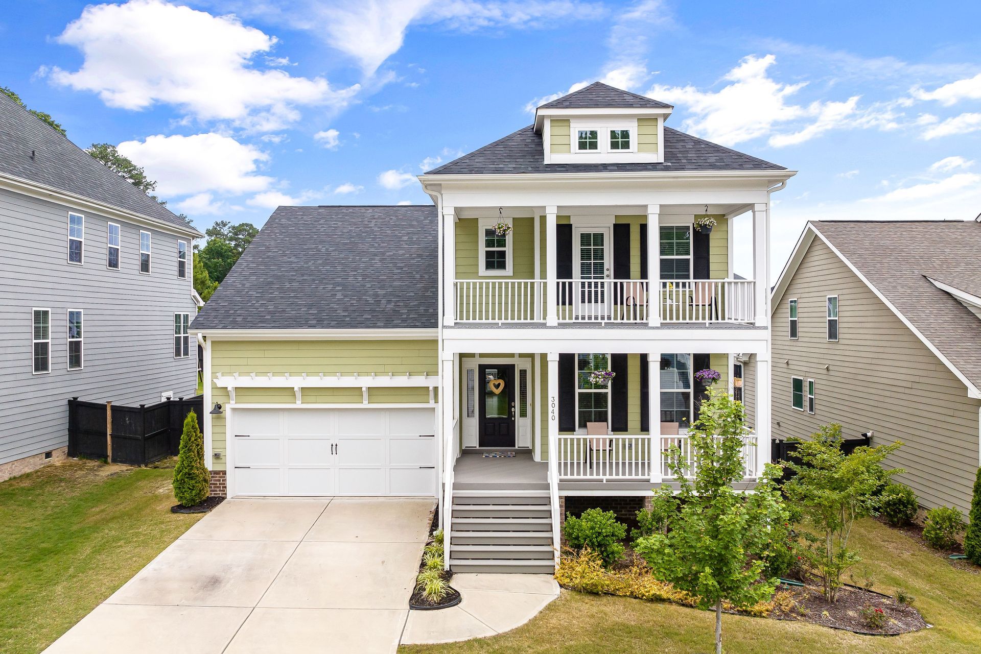 Two-story house with white trim, front porch, garage, and driveway under a partly cloudy sky