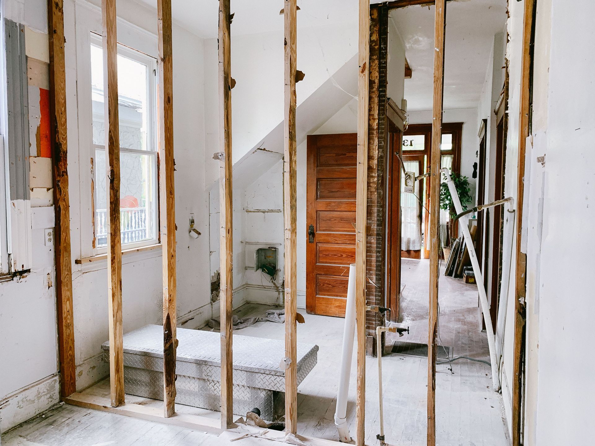 Interior renovation with exposed wall studs, unfinished drywall, and a partially built stairway