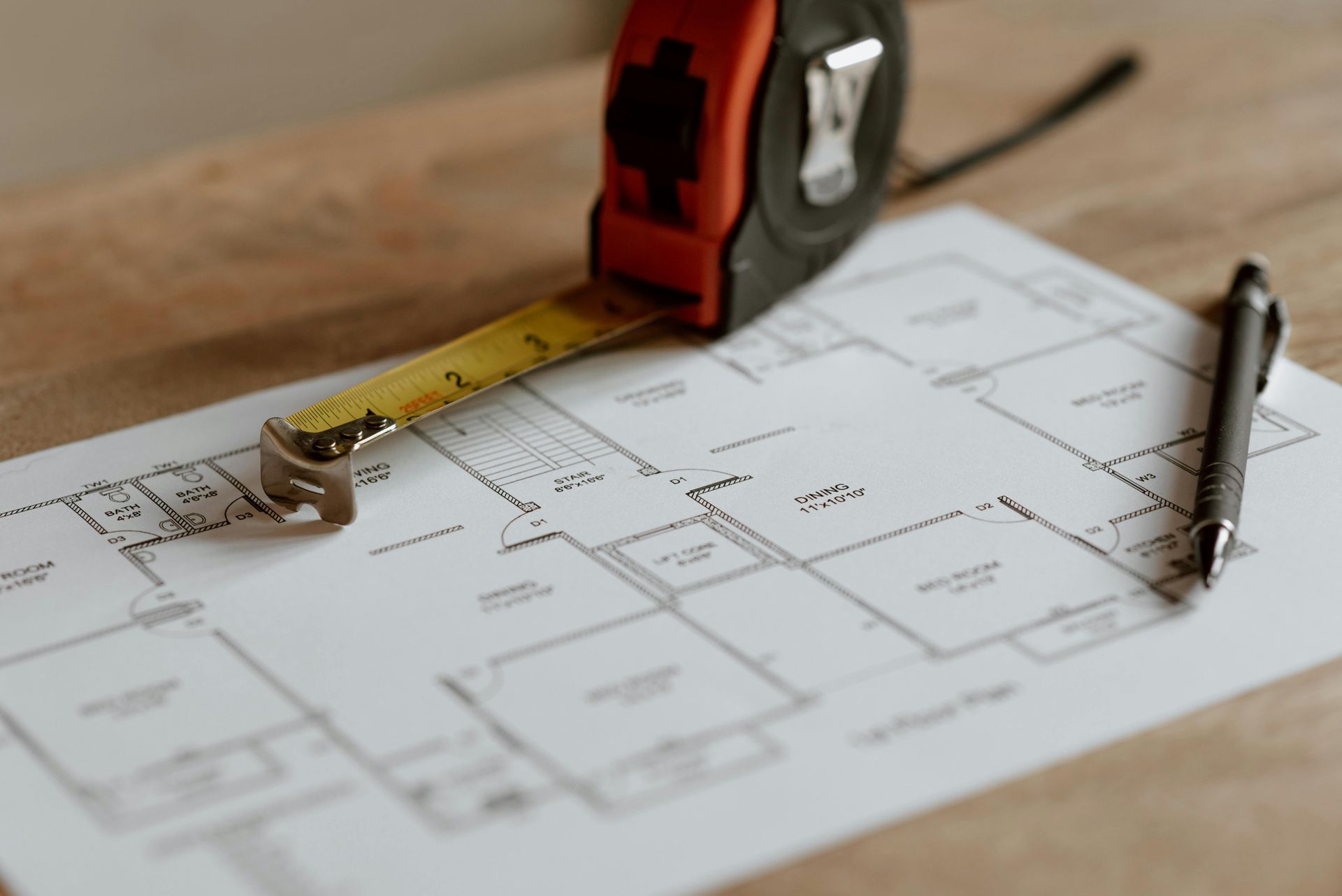 Measuring tape, floor plan, and pen on a table, suggesting home design or renovation planning
