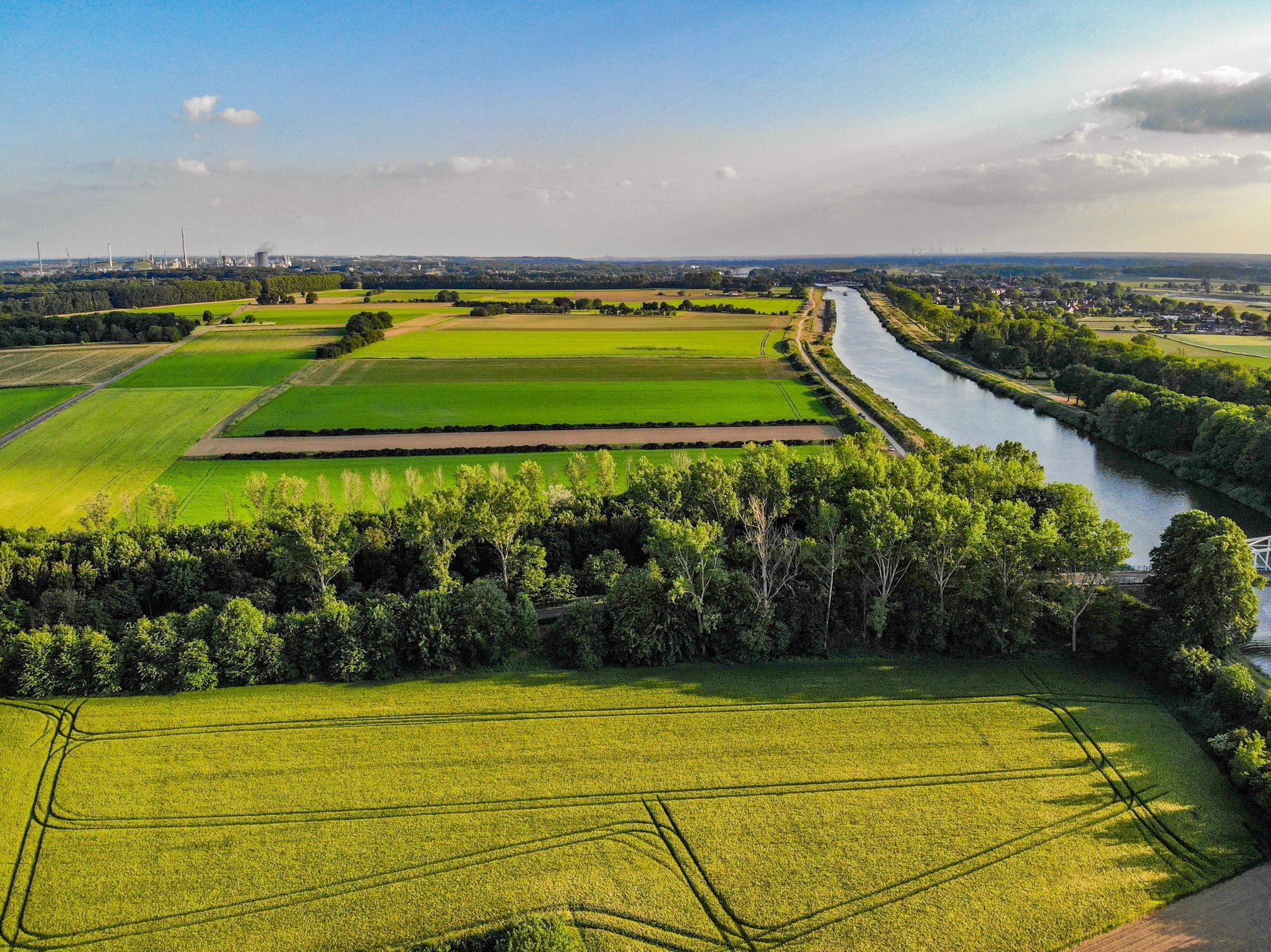 Aerial view of green farmland beside a winding river under a clear blue sky