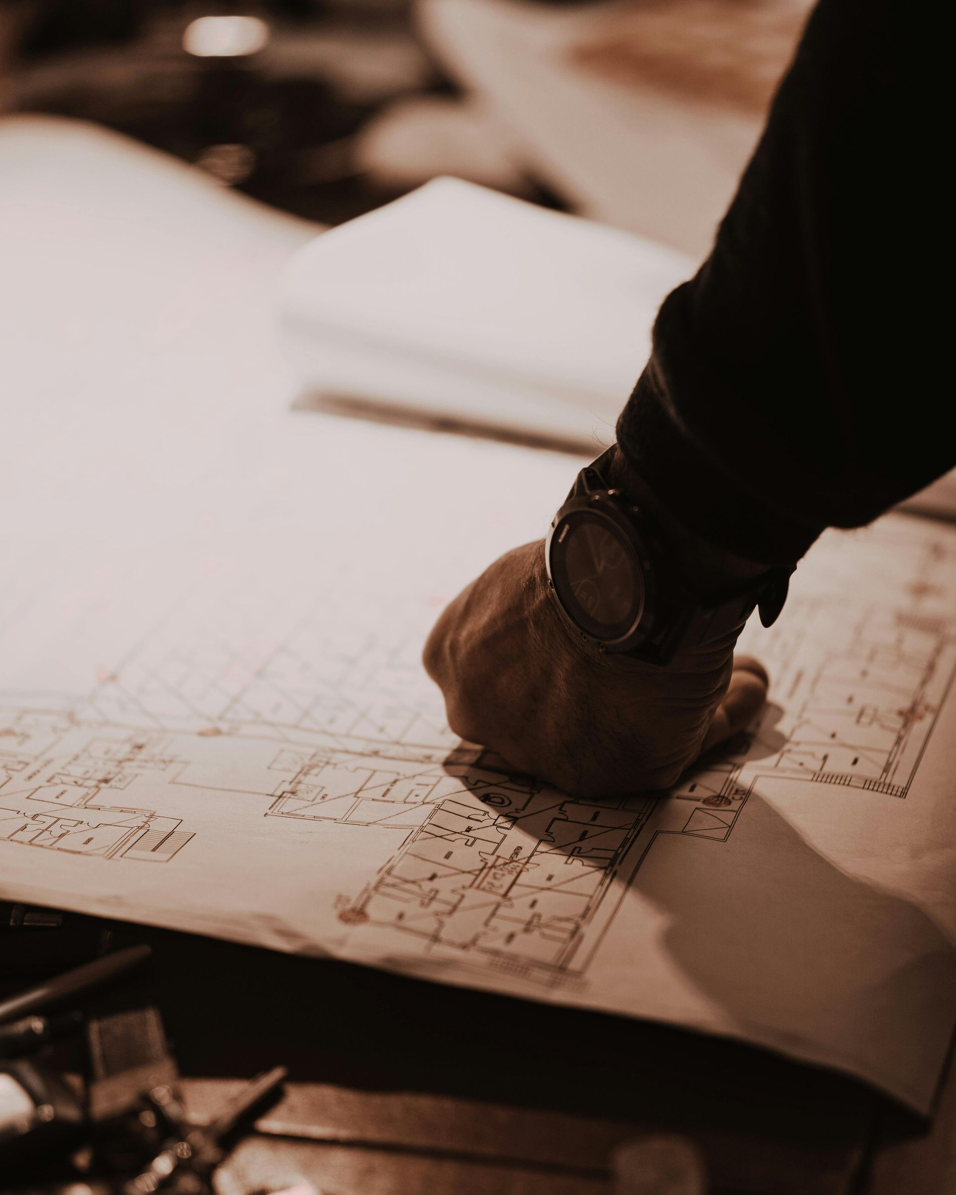 Hand drawing on architectural blueprints under warm light