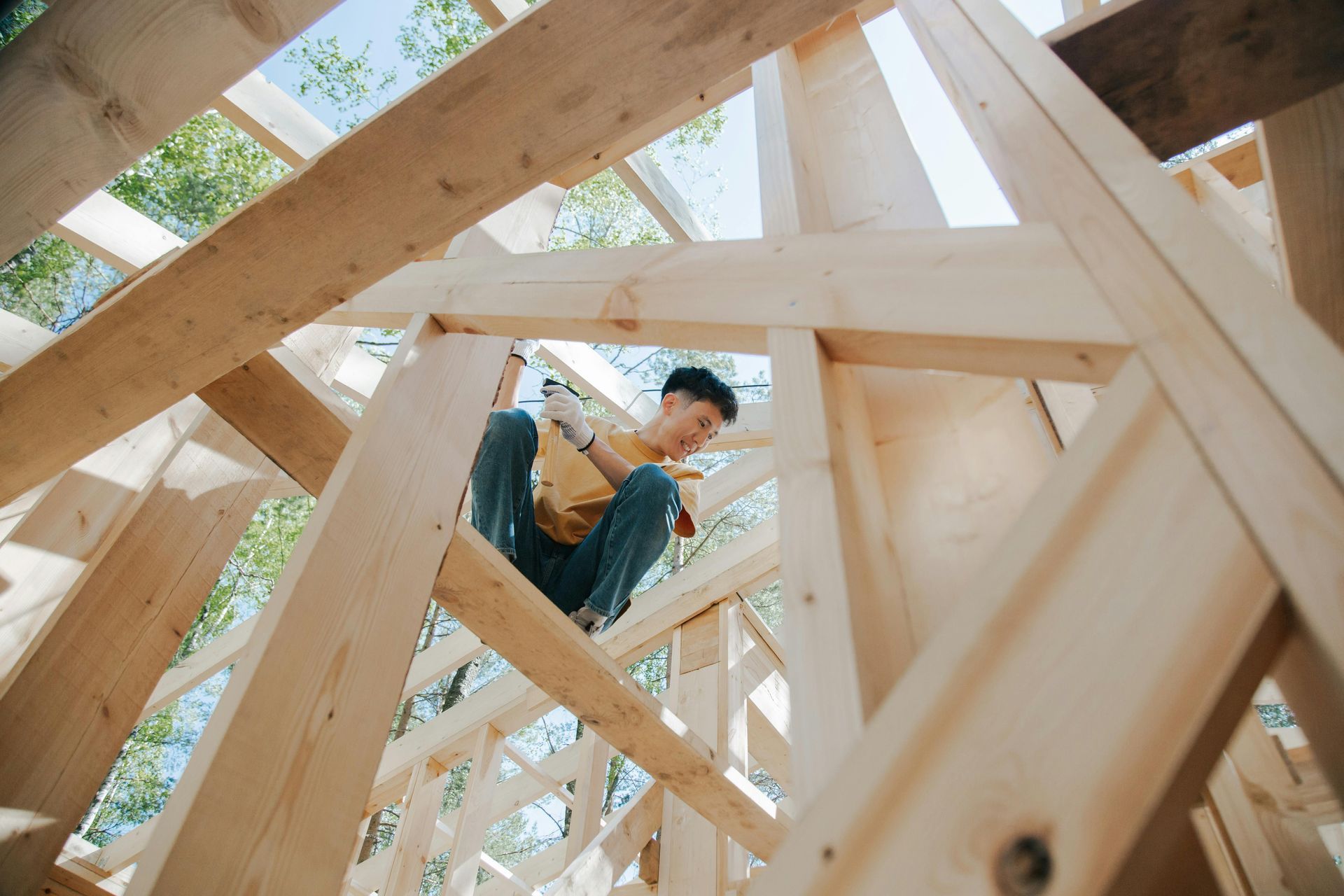 Person working on wooden frame construction; sunny outdoors.