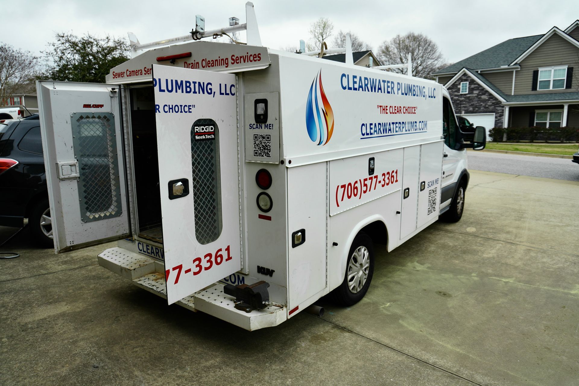 White plumbing service van with the door open in a residential area.