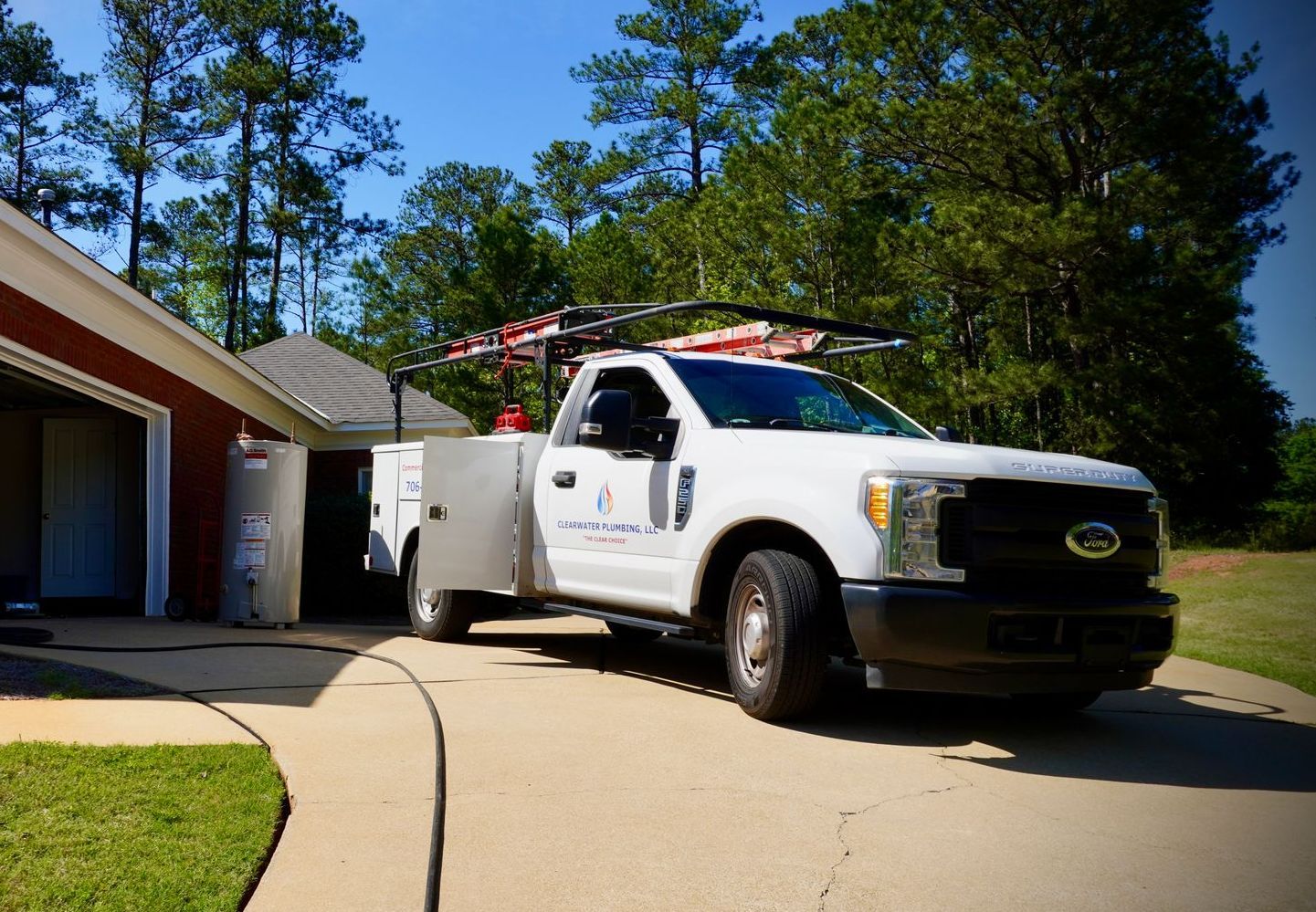 White service truck parked in driveway, near a red building.