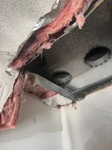 Damaged ceiling area with exposed insulation, ductwork, and aluminum tape.