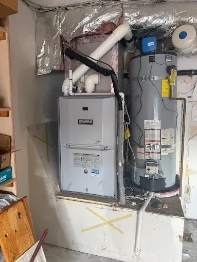 Furnace and water heater in a utility room; white, grey, and metal colored appliances.