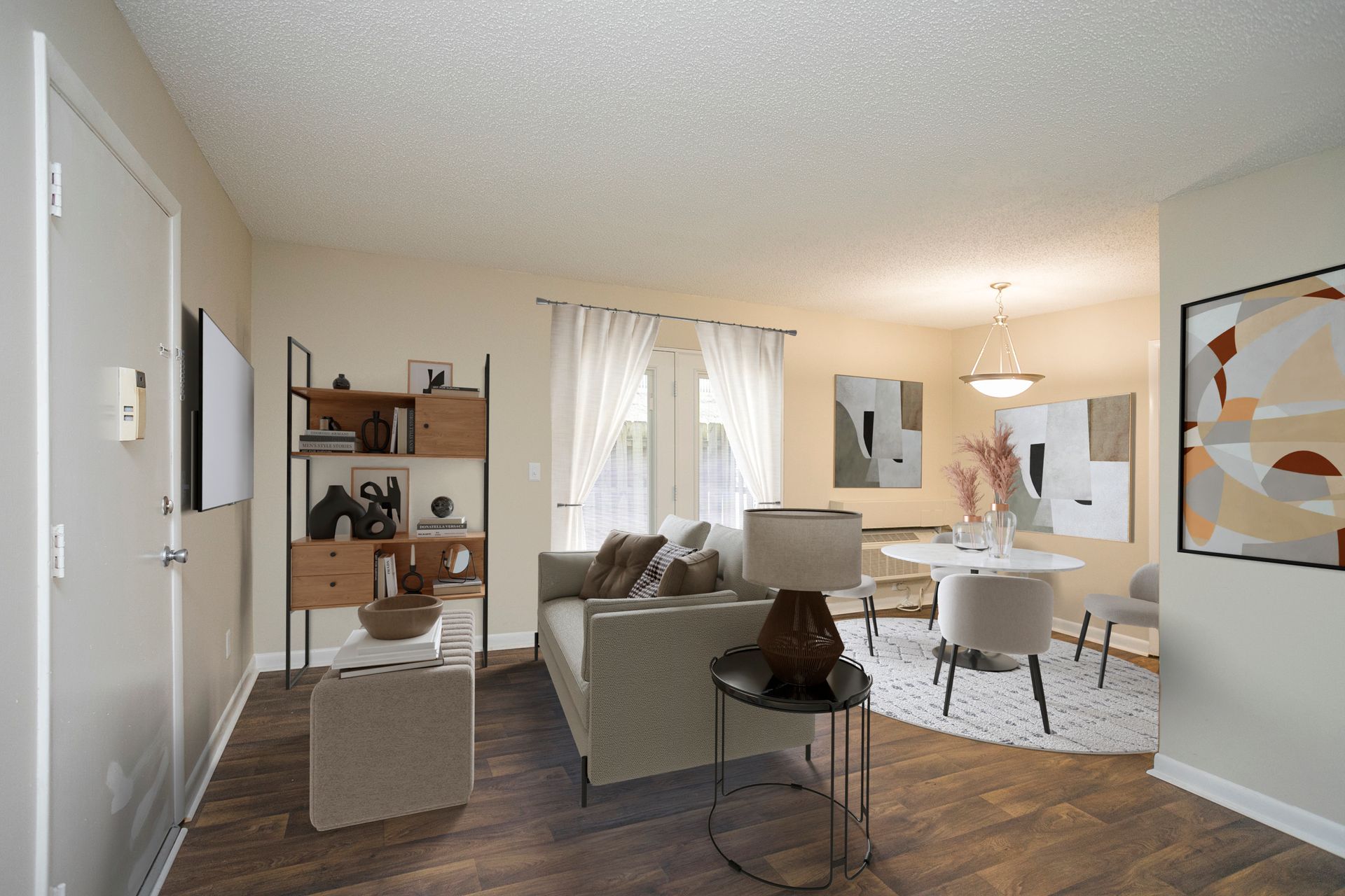 A bright, modern living and dining room with a sofa, shelving unit, and round dining table on a light wood floor.