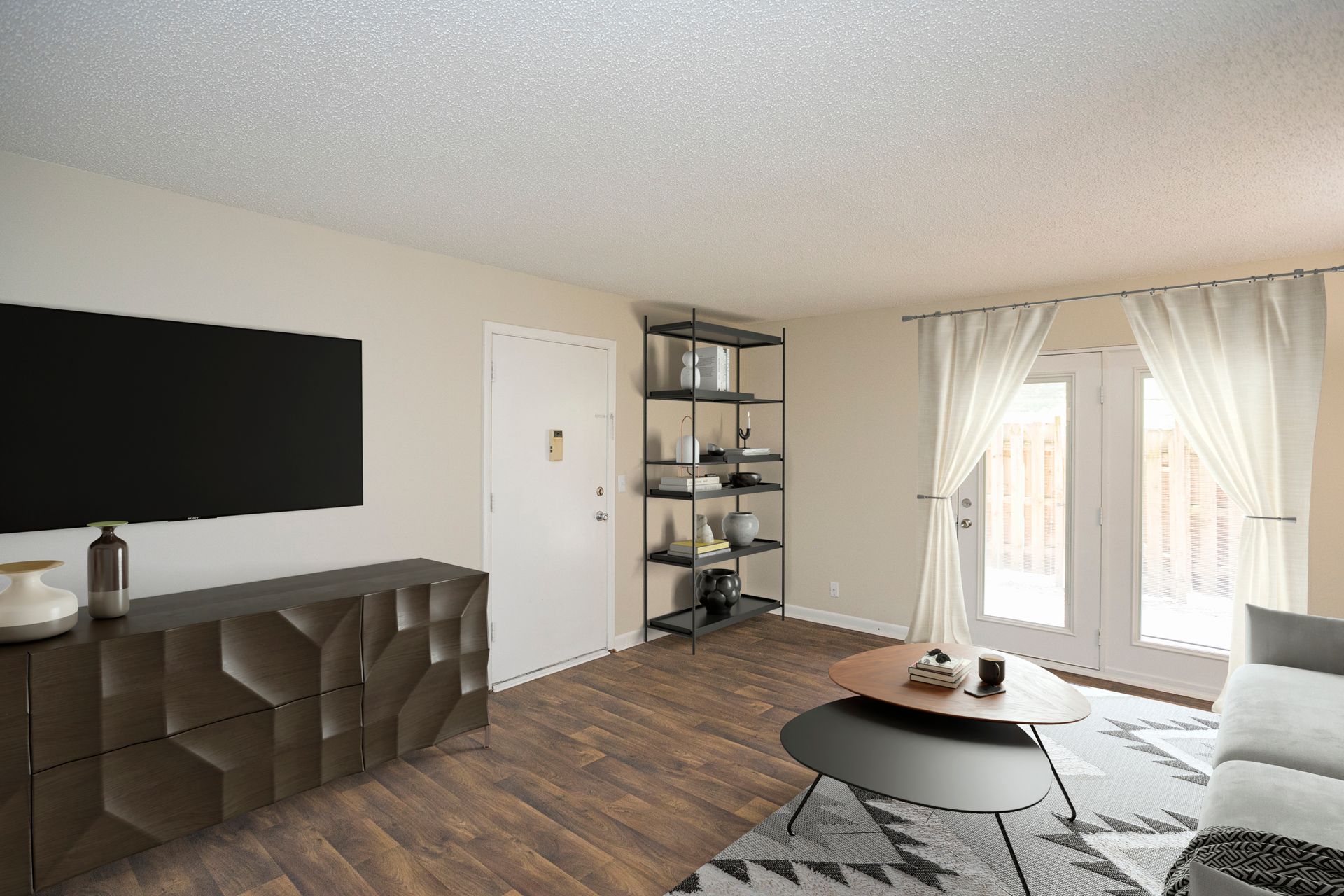 Modern living room with a dark geometric media console, a wall-mounted TV, open shelving, and glass doors with white drapes.