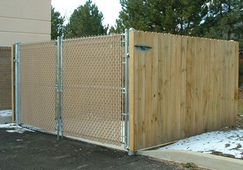 A chain link fence with a wooden fence behind it