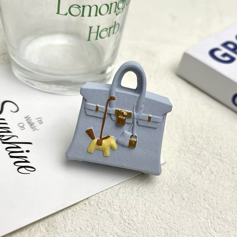 A purse with a horse on it is on a piece of paper next to a glass that says lemon herb