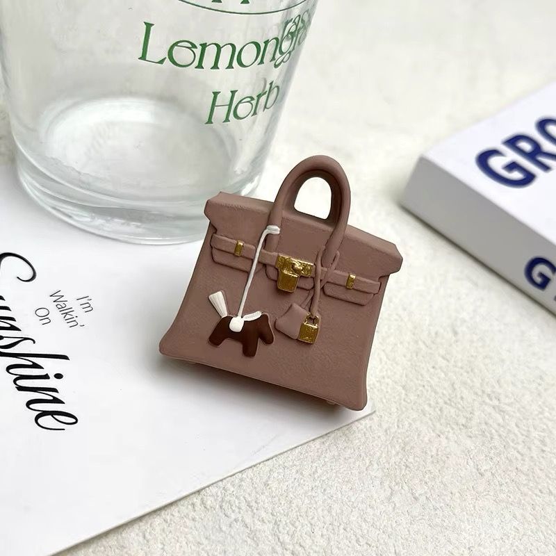 A small purse is sitting on a piece of paper next to a glass and a book.