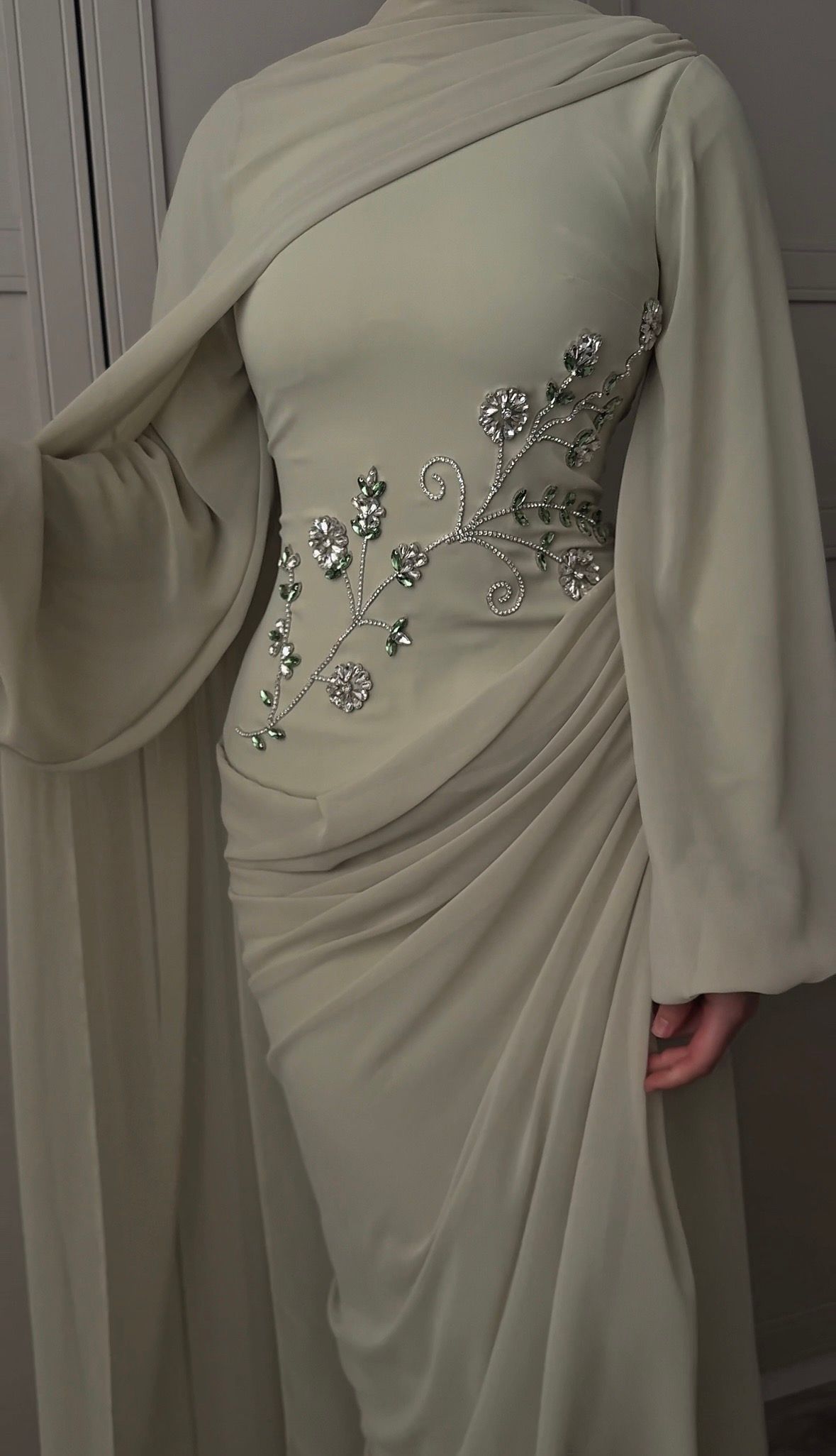 Beige draped gown with jeweled floral embellishment on the side and shoulder overlay