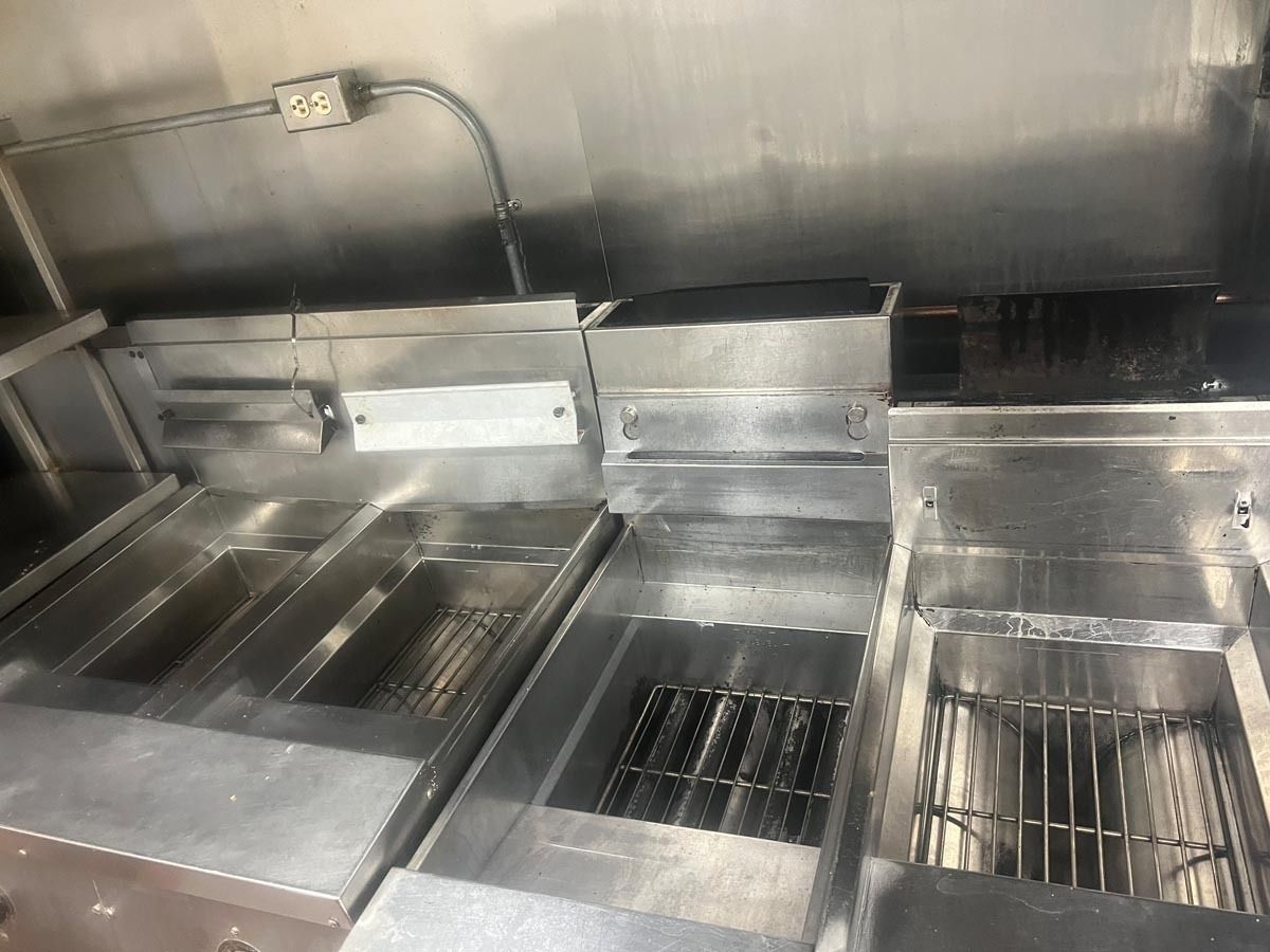 A stainless steel kitchen with two fryers and a stove.