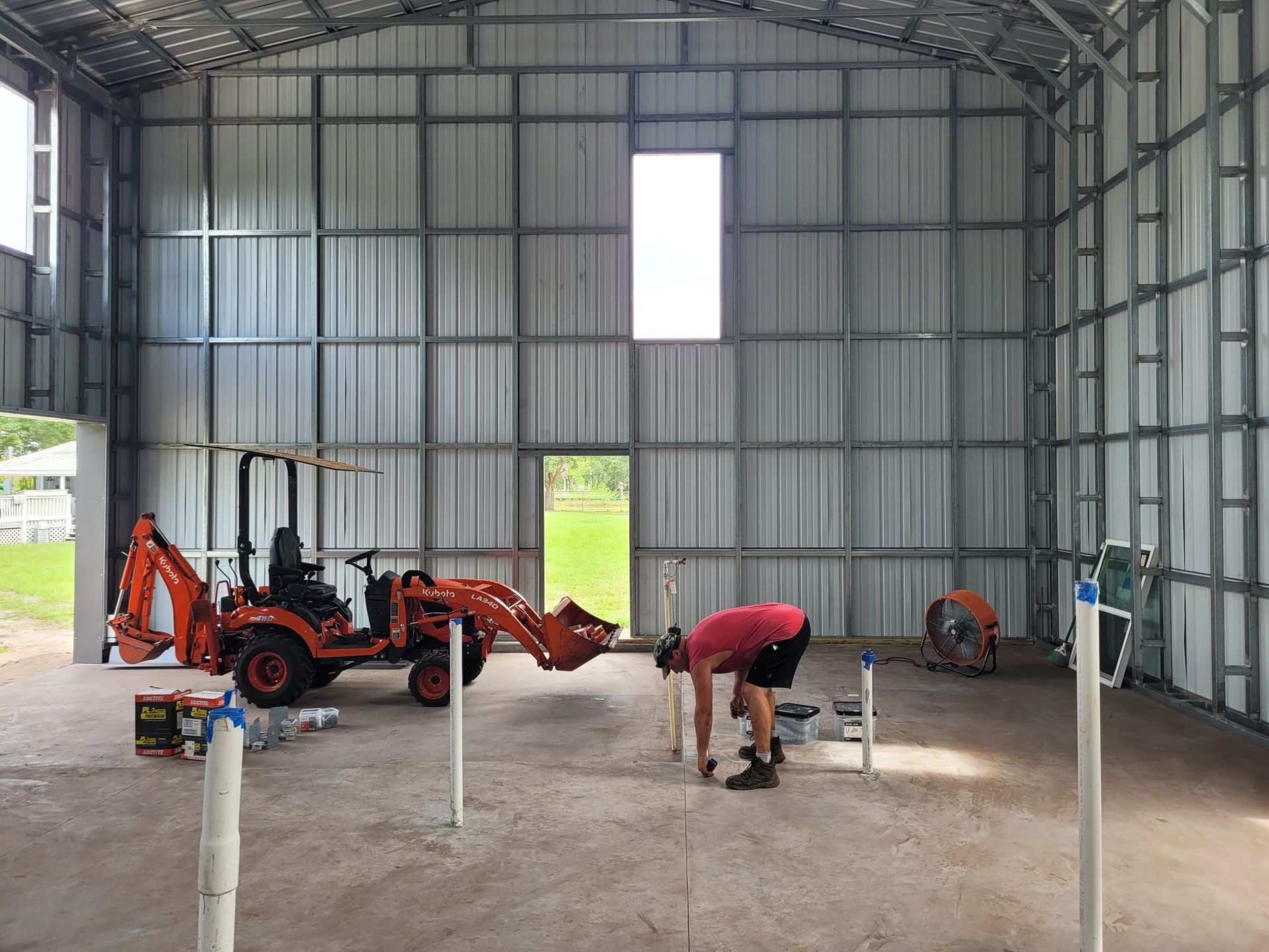 A man is working in a metal building next to a tractor.