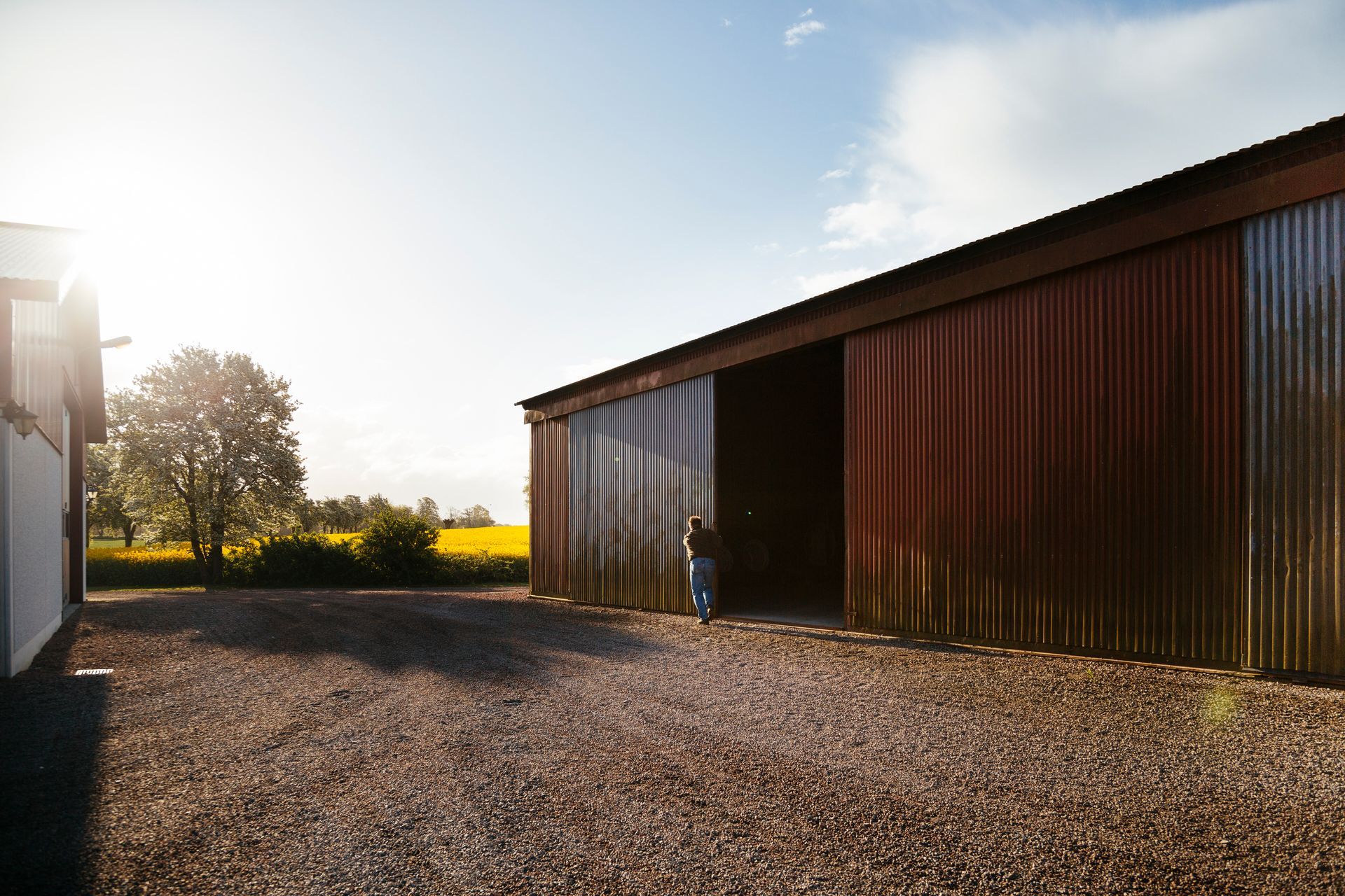 A man is standing in front of a barn with a sliding door.