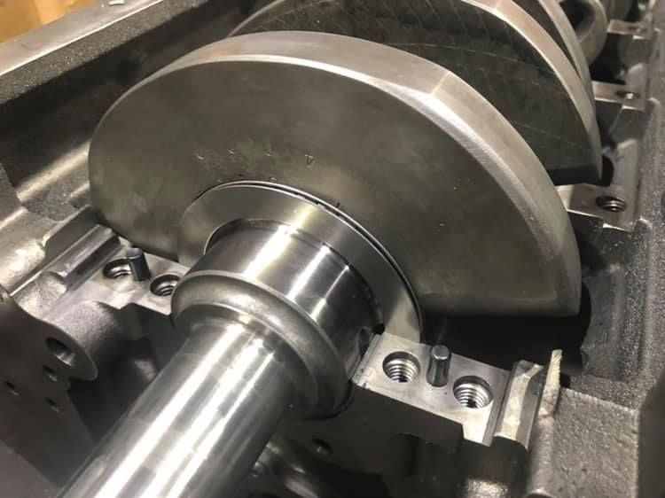 A close up of a metal crankshaft with a bearing on it.