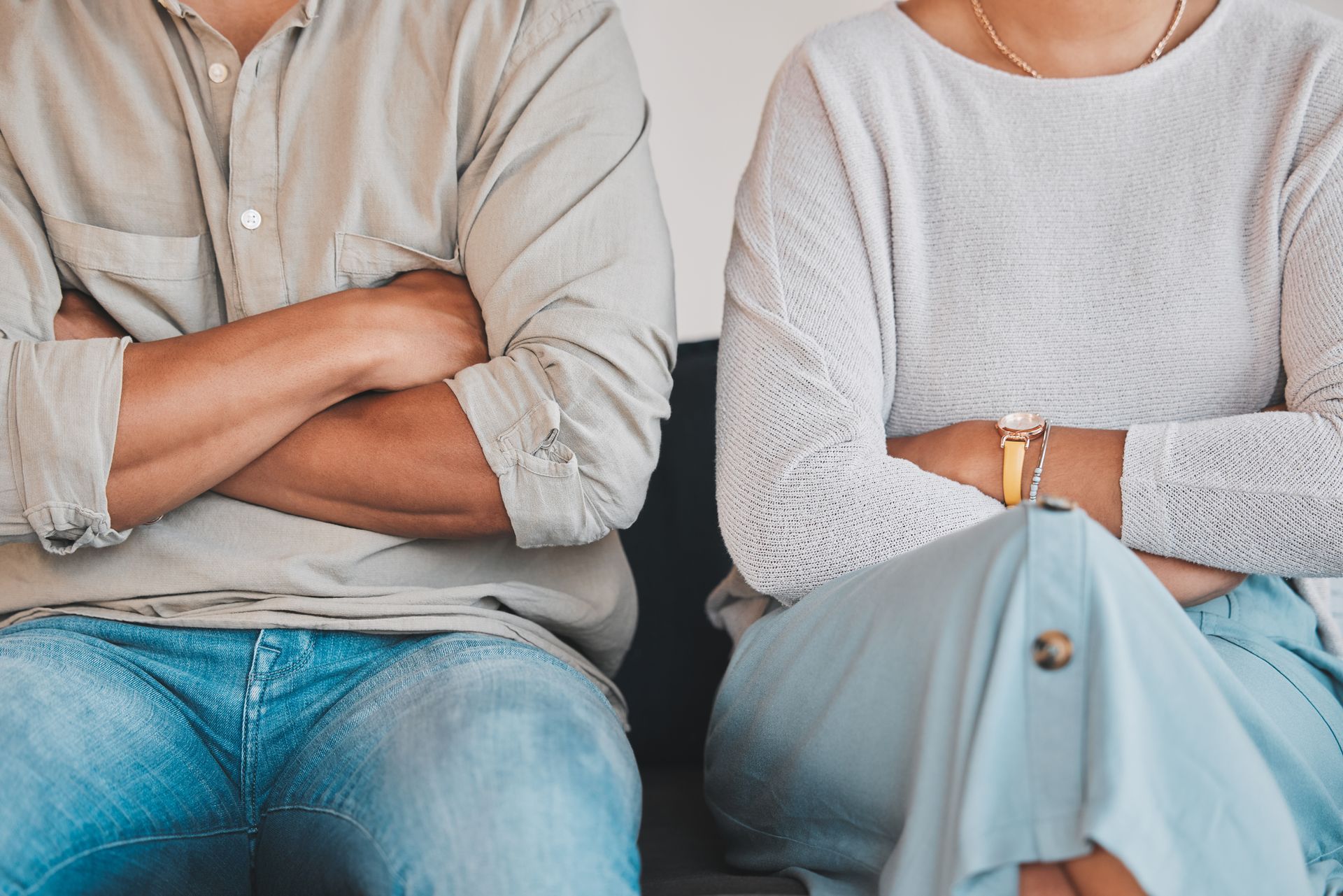 A man and a woman are sitting next to each other with their arms crossed.