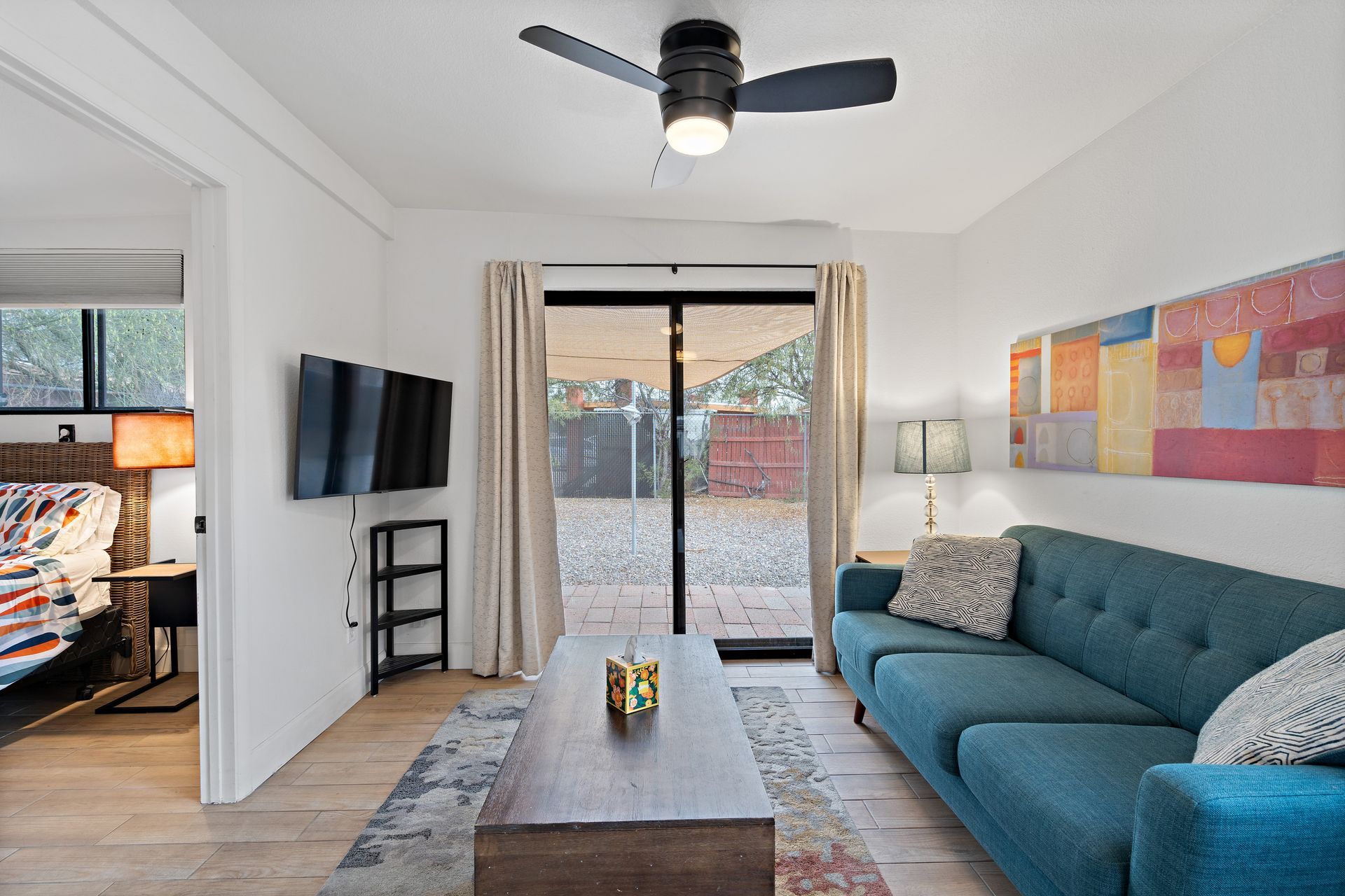 Living room with teal sofa, TV, and sliding door to a patio.