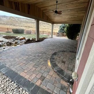Brick patio under a wooden porch with a mountain view and landscaping.